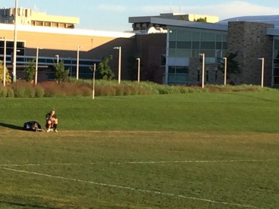 College soccer player sitting on soccer ball waiting for summer practice