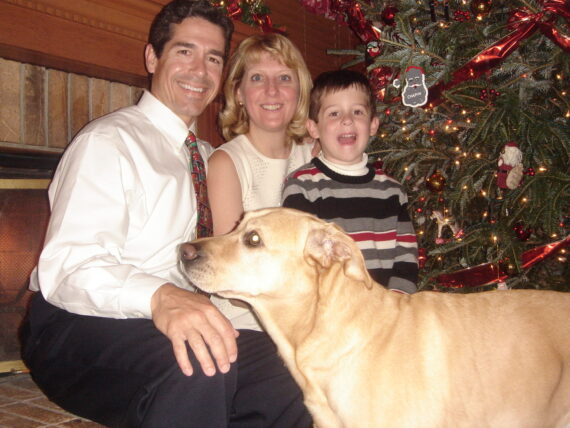 Family with dog next to Christmas tree