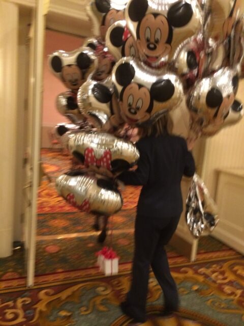 Person carrying lots of Mickey Mouse balloons