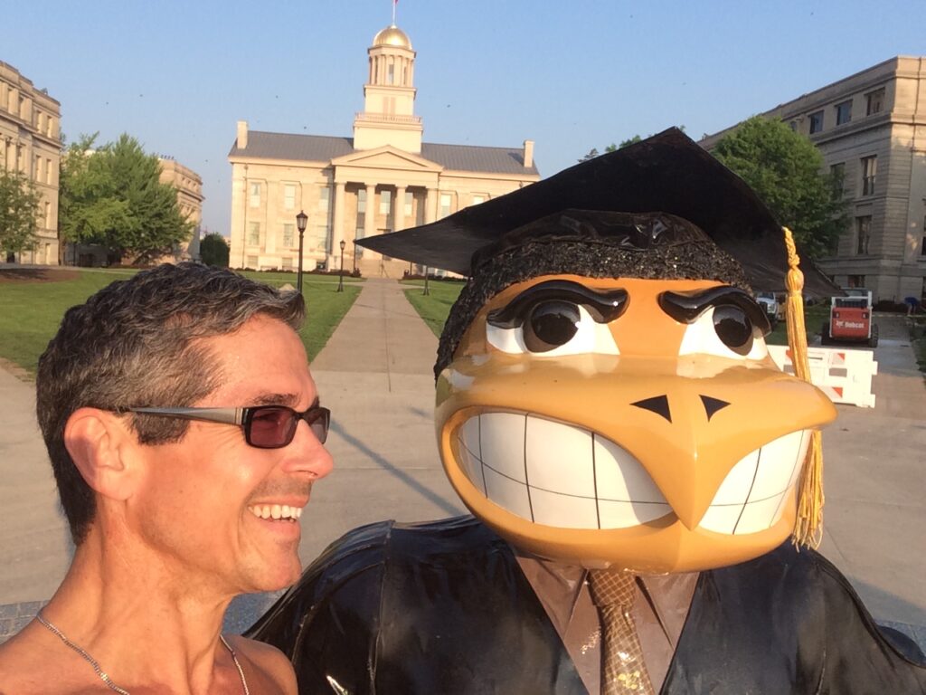 University of Iowa statue and shirtless man posing for camera