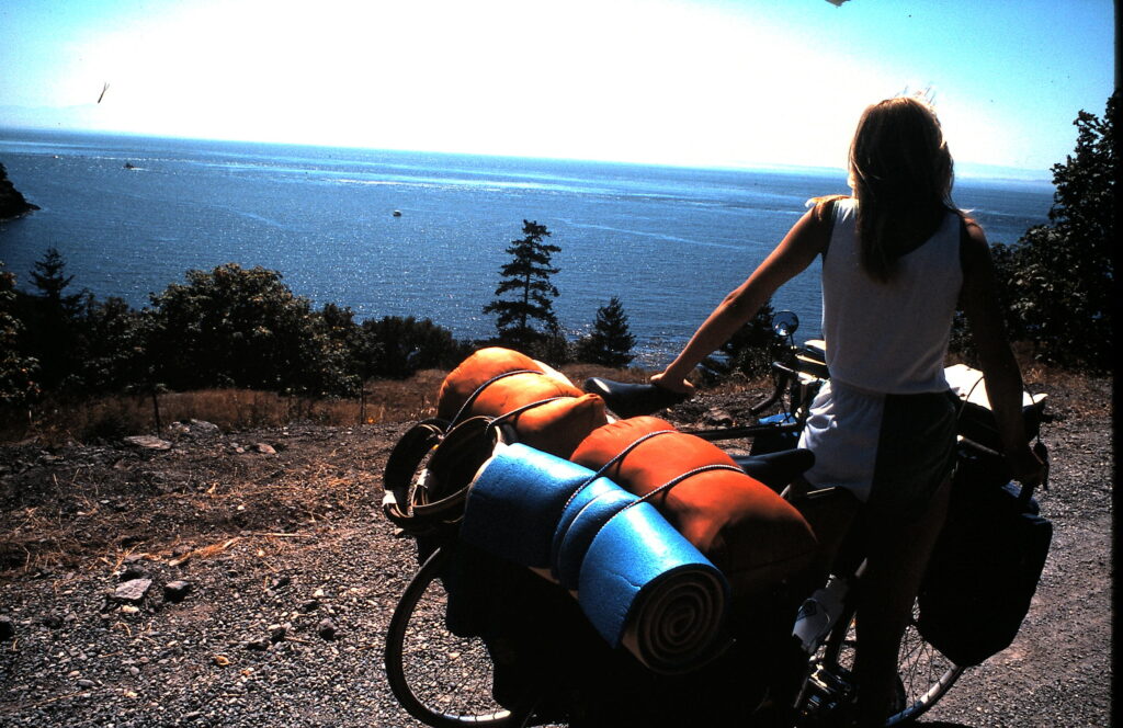woman with two touring bicycles while gazing at ocean