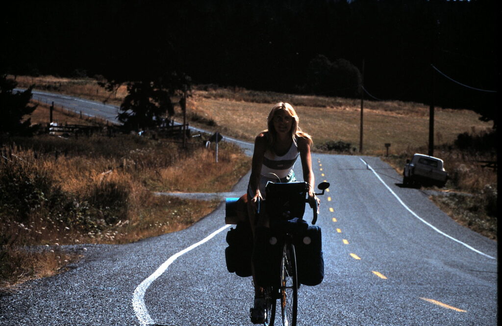 woman riding touring bicycle on country road