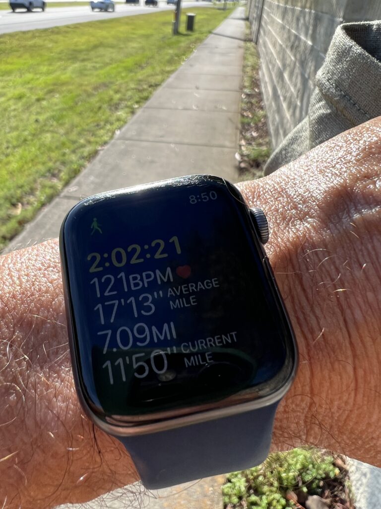 Apple Watch on wrist with sidewalk in background