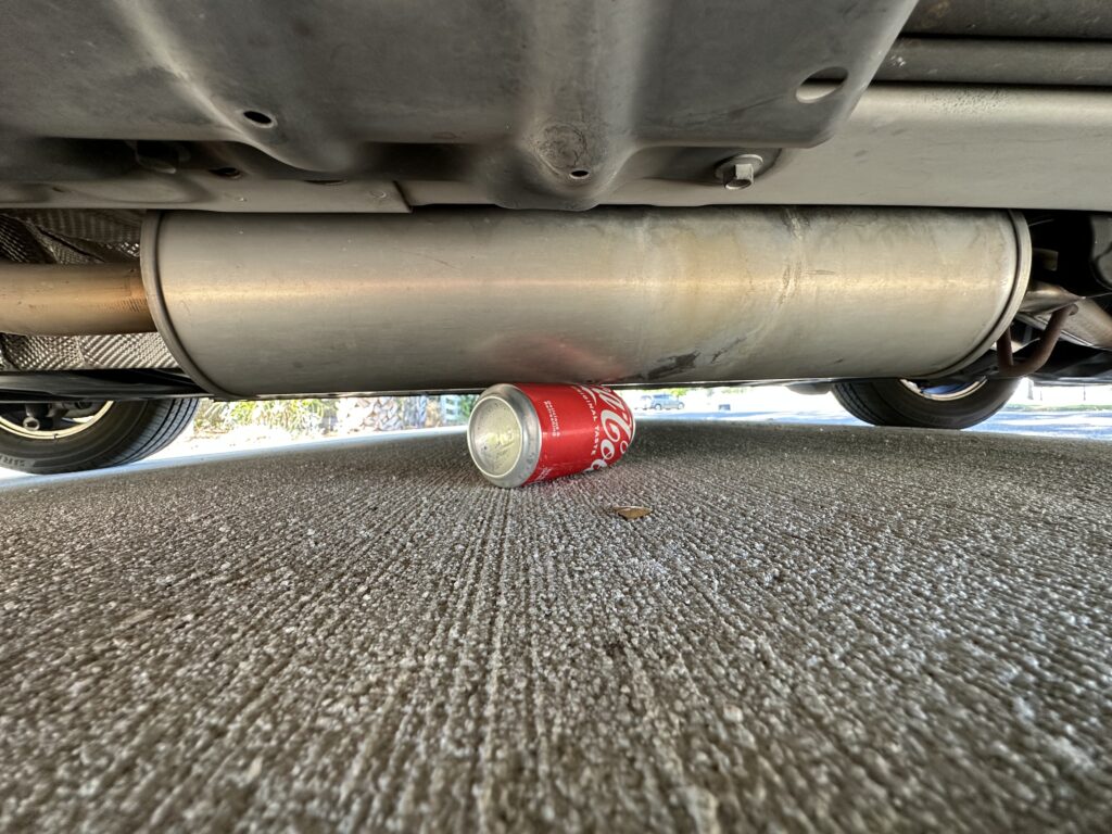 Coke can next to a muffler on the undercarriage of a van