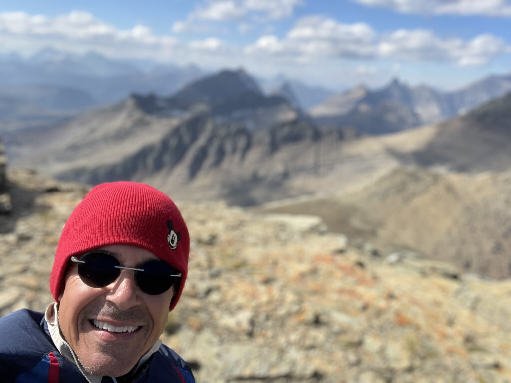 man wearing red hat and sunglasses on a mountain
