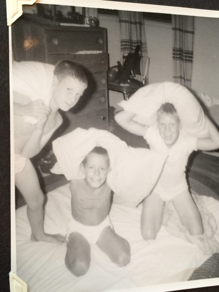 Black and white photo of three kids having a pillow fight