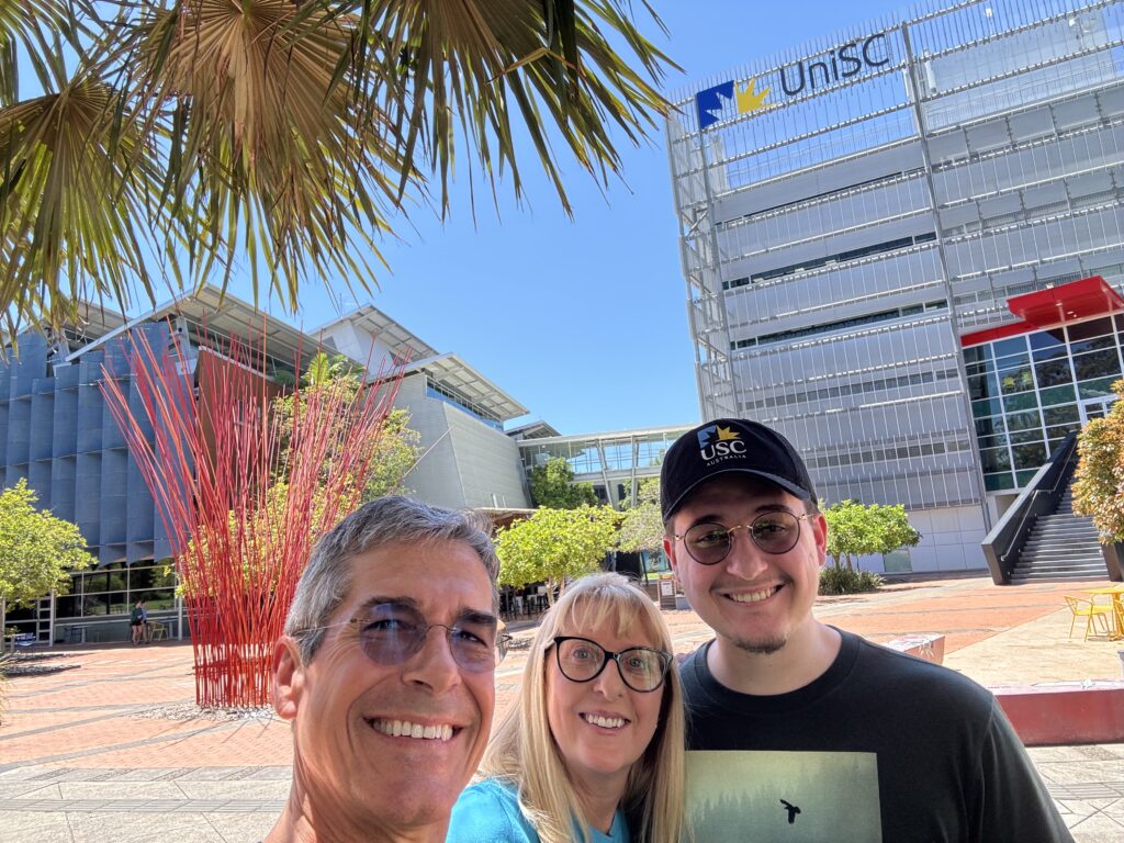 Three adults posing on a college campus