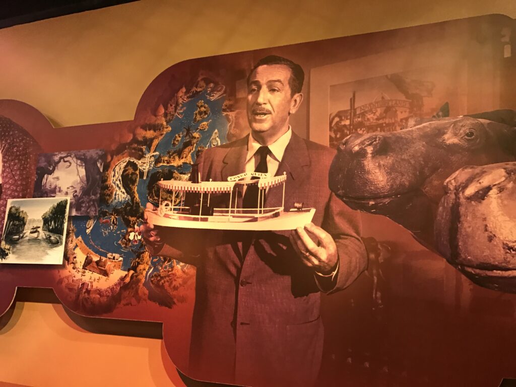 Walt Disney holding a small model of a Jungle Cruise boat