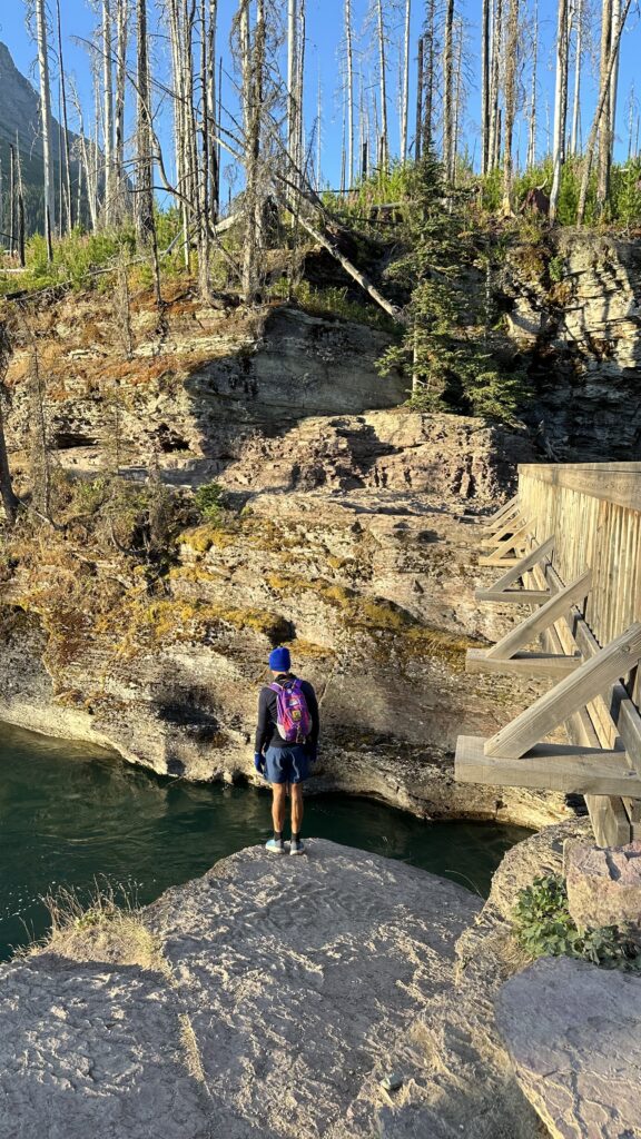 Person standing next to mountain stream