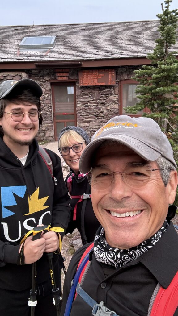 Three people outside a high mountain chalet