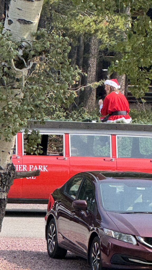 Santa sitting atop a big red station wagon